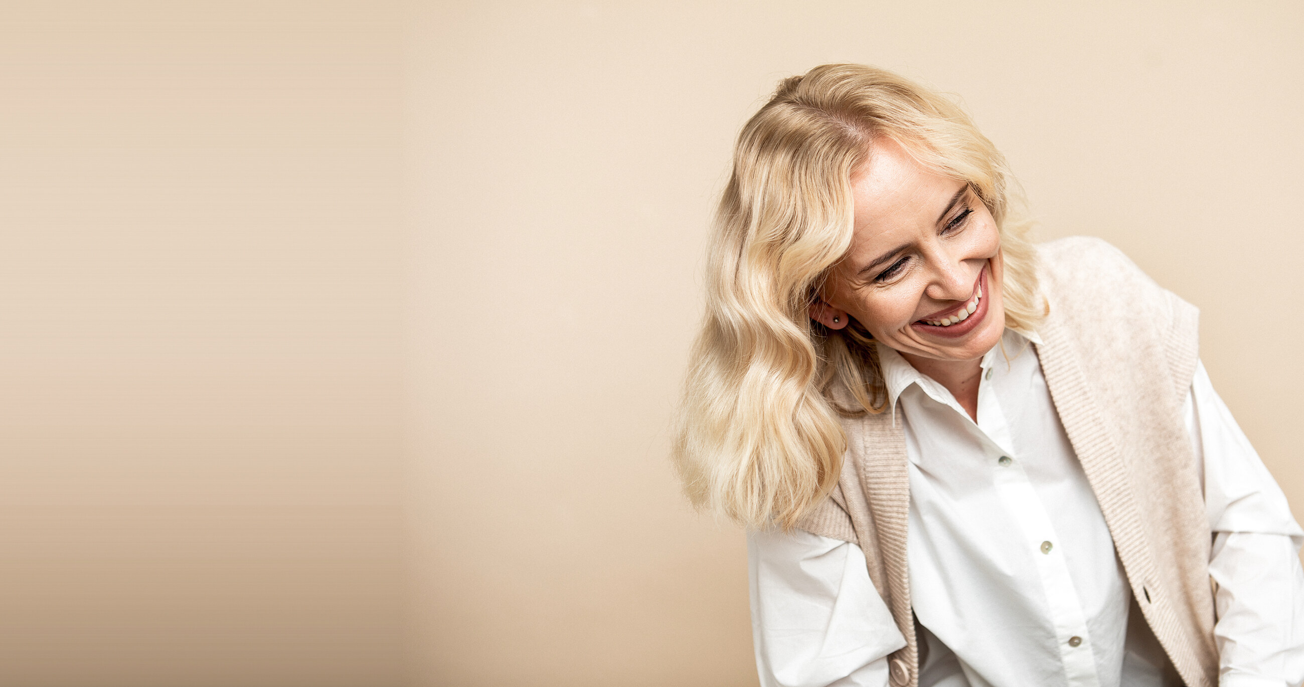 Milla Törmälä laughing, photographed against a warm studio backdrop